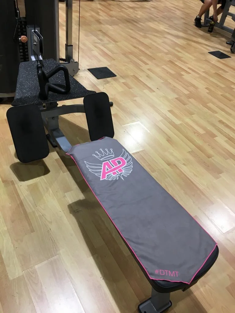 Toalla gris oscuro con borde rosa extendida sobre un banco plano