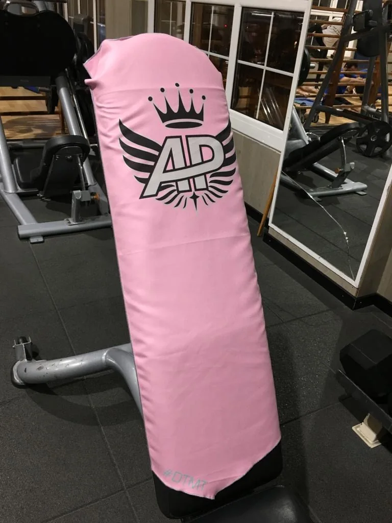 Toalla rosa con logo AP sujeta al respaldo de una máquina